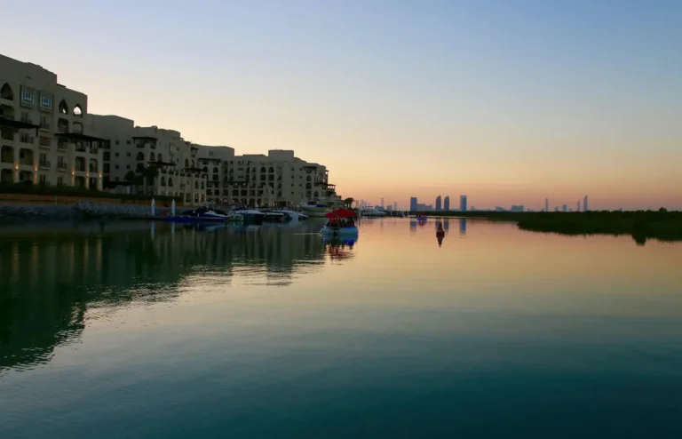 Paseo marítimo con edificios y barcos junto al agua al atardecer