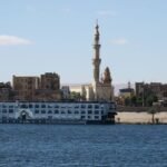 Barco de crucero navegando por el Nilo junto a una mezquita en Asuán