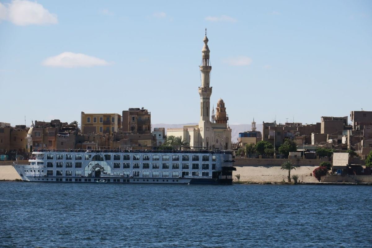 Barco de crucero navegando por el Nilo junto a una mezquita en Asuán